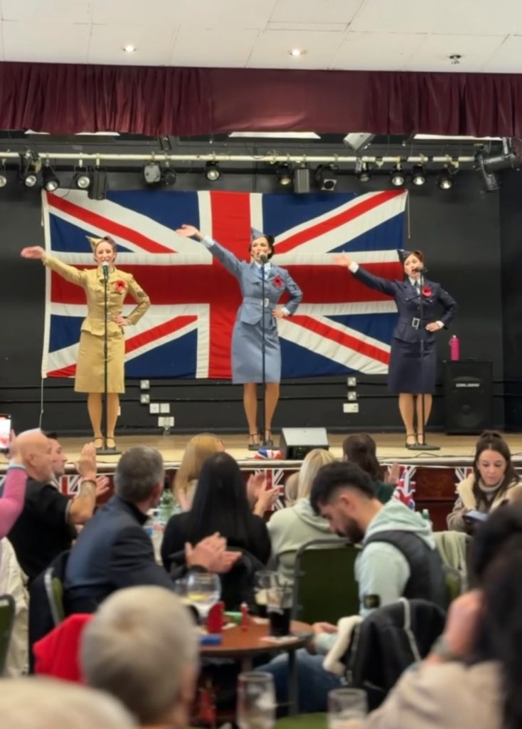 Three singers performing in front of a Union flag at Greasbrough’s 2025 Remembrance event.
